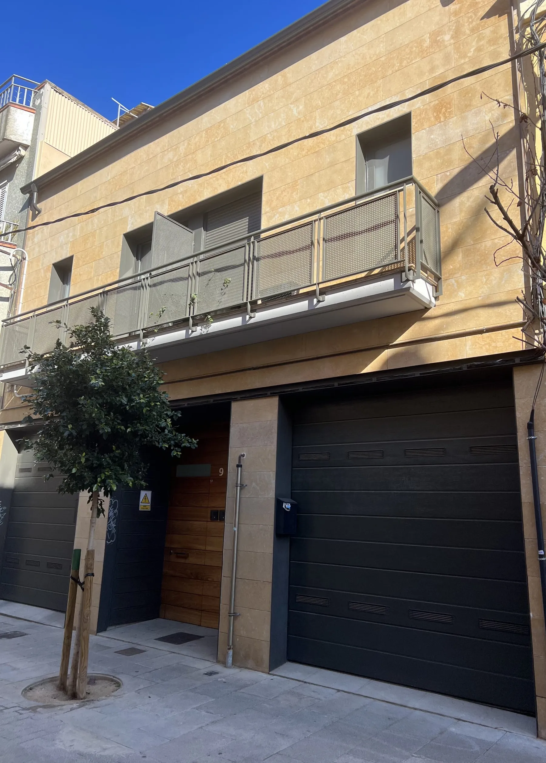 Casa pareada terminada en Cornellà de Llobregat: fachada de piedra clara, balcón con barandilla metálica y garaje