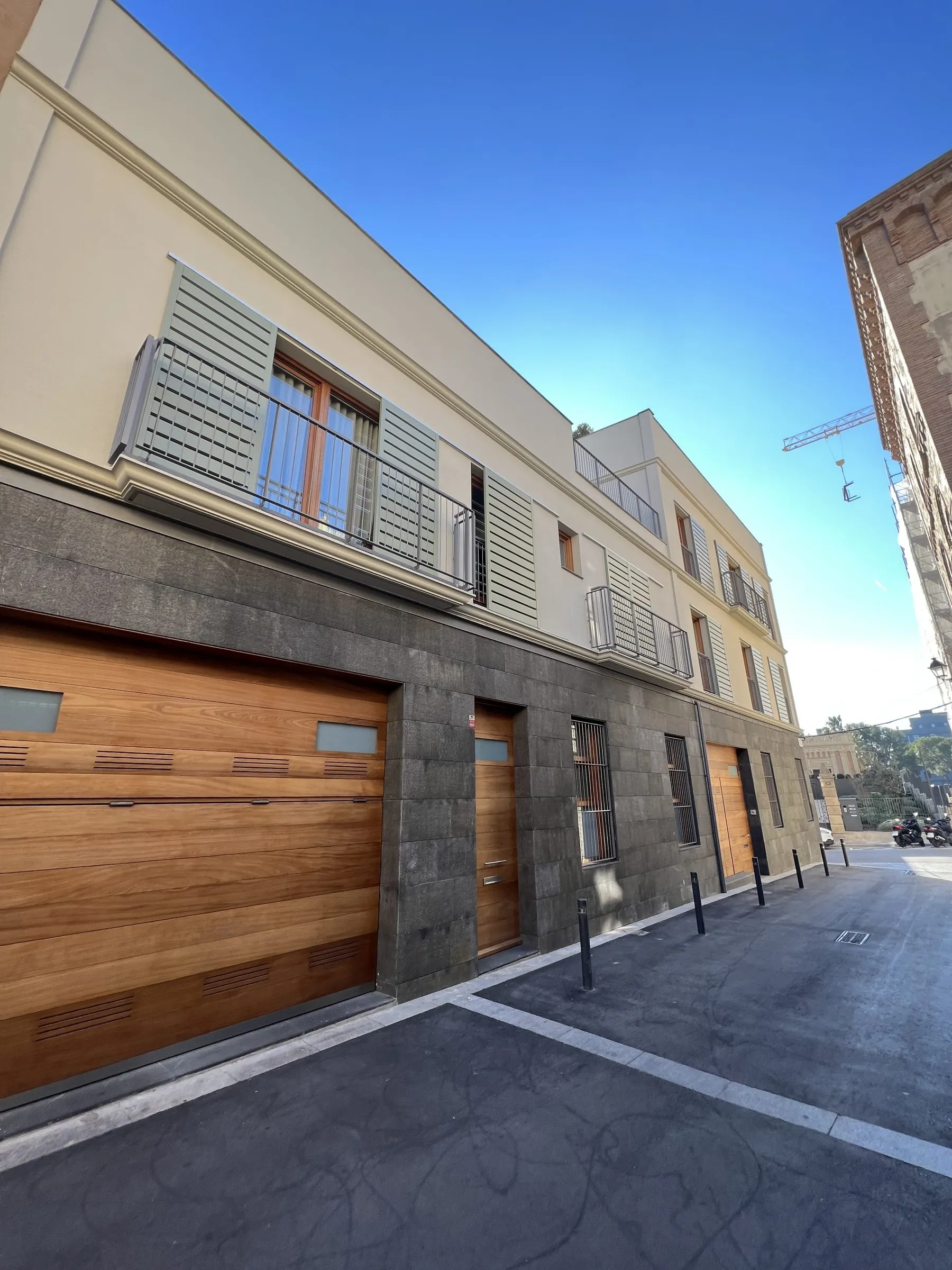 Fachada de piedra y madera de una casa terminada en Sarrià, fotografiada desde la calle