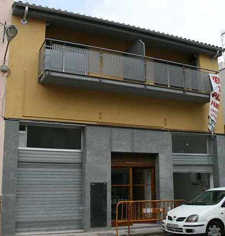 Pequeño edificio de dúplex con fachada amarilla y balcón metálico
